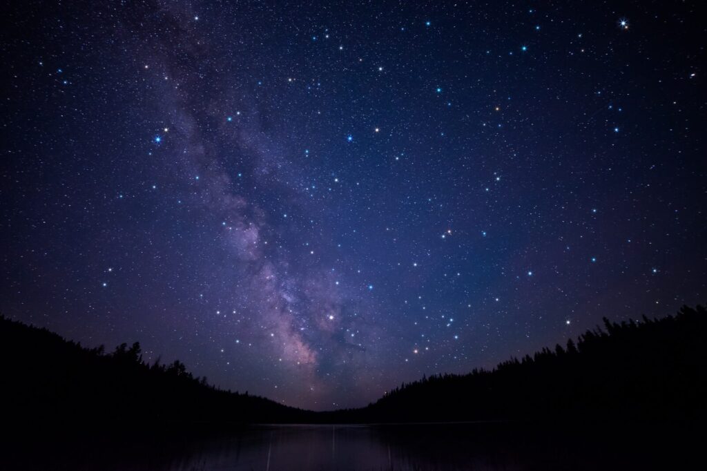 Stargazing scene with starry night sky over hilltops in summer as a no-spend activity inspiration