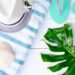 Summer beach flat lay with hat, towel, flip flops, and shells for no-spend vacation inspiration
