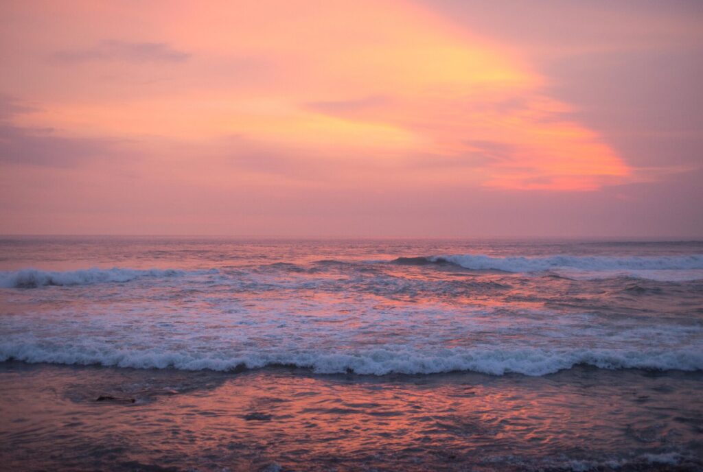 colorful sunset in orange hues over foamy beach waves as an inspiration for no-spend activities