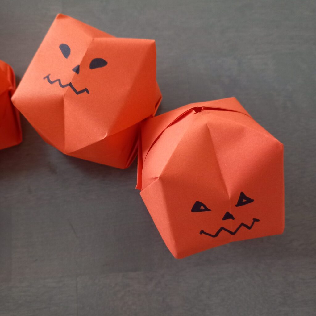pumpkin origami with face Halloween origami lanterns with pumpkin faces drawn for seasonal string lights.